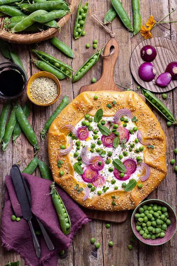 Galette con piselli, menta, cipolle rosse e fiocchi di latte, vista dall'alto su un tavolo di legno