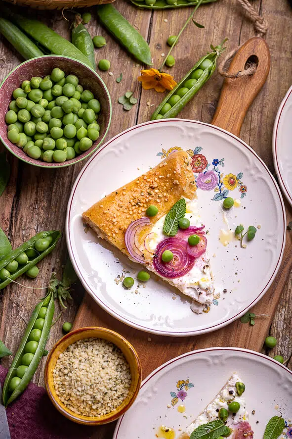 Galette con piselli, menta, cipolle rosse e fiocchi di latte, una fetta su un piattino decorato con fiori, vista dall'alto