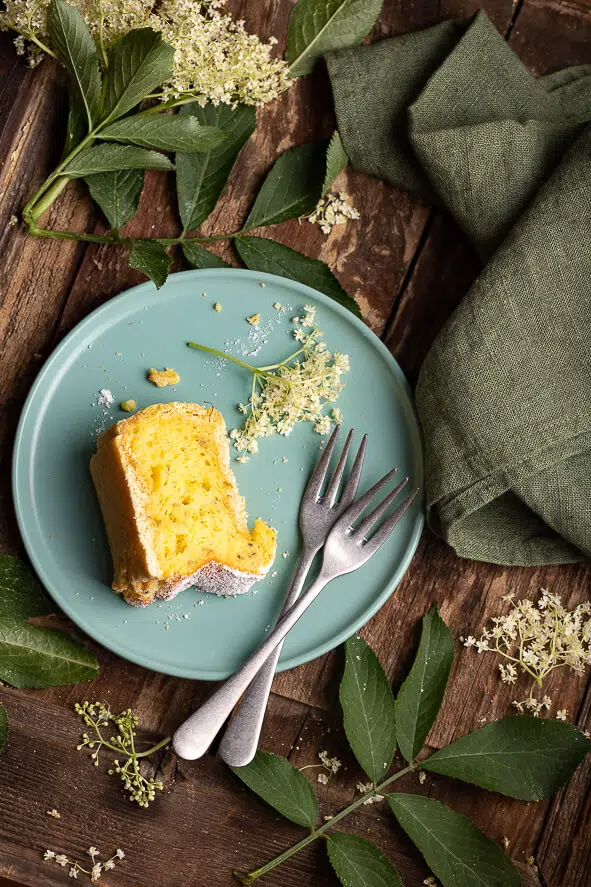 Fetta di torta di ricotta e fiori di sambuco su un piattino con due forchette