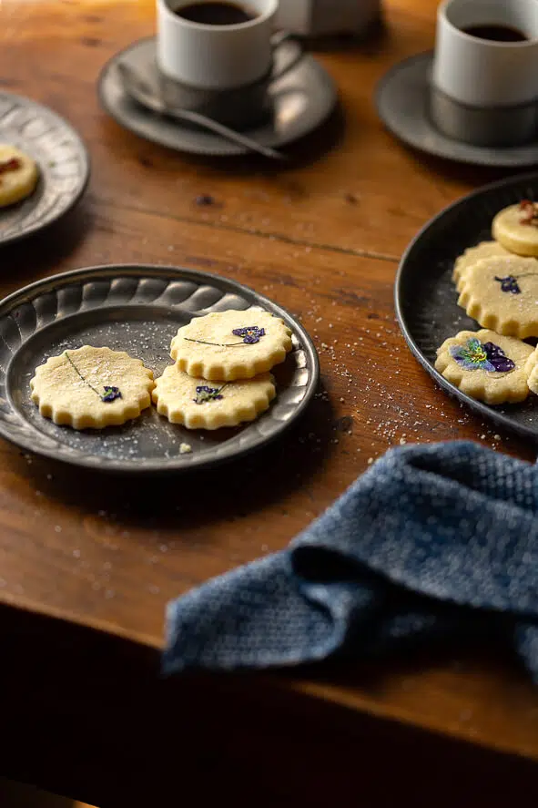 Piattino von biscotti con fiori eduli su tavolo di legno